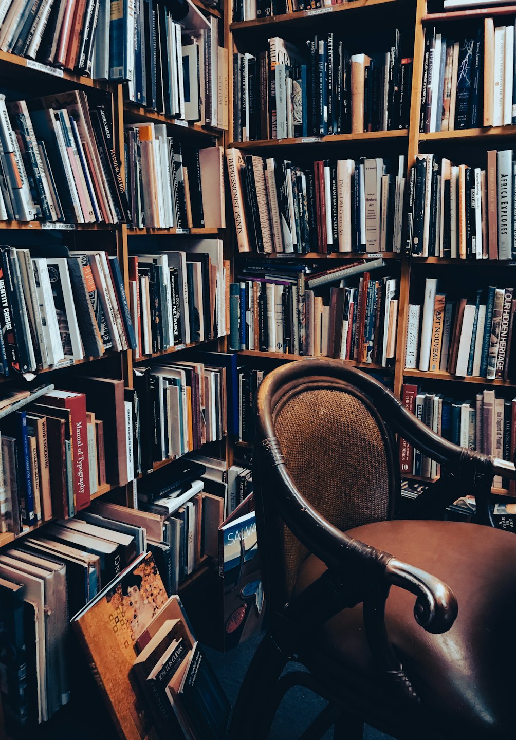 Accogliente angolo libreria con scaffali stracolmi e poltrona.